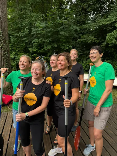 Das Frauenteam in SÜDKOLA- und ZITRONENSTOLZ-Shirts mit Paddeln am Steg, vor dem Start